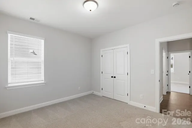 a view of an empty room with closet and a window