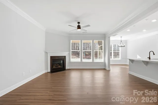 a view of a livingroom with wooden floor a fireplace and windows
