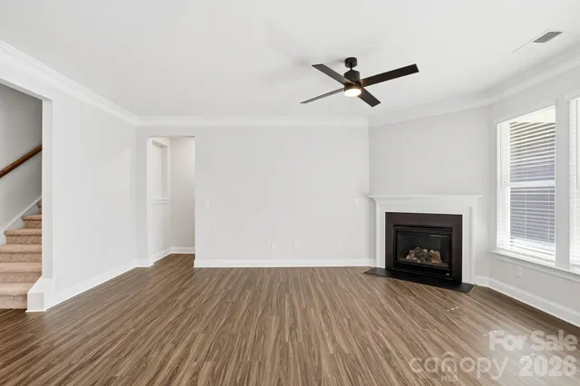 an empty room with wooden floor a fireplace and windows