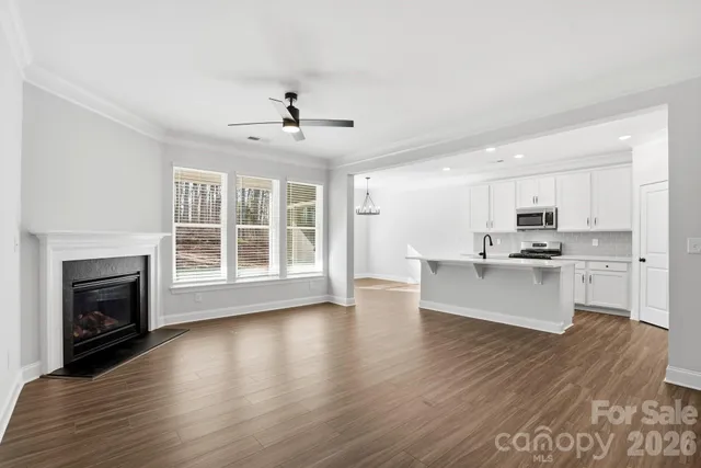 a view of an empty room with kitchen and fireplace