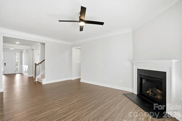 a view of an empty room with wooden floor a fireplace