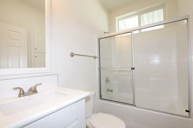 a bathroom with a granite countertop sink toilet a mirror and shower