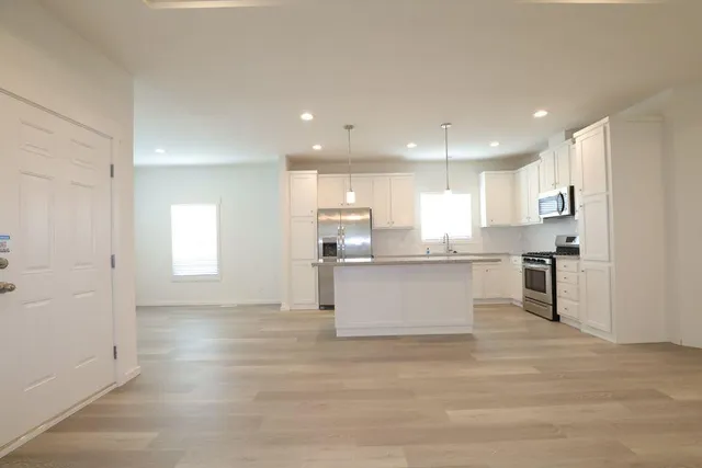 a view of kitchen with kitchen island sink refrigerator and white cabinets