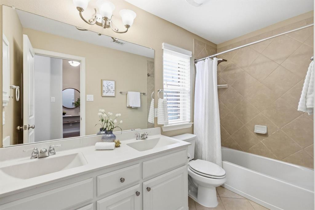 9728 Bitterroot Drive Little Elm, TX 75068 - Photo 27 of 39 Secondary bathroom with dual sinks, cabinets, natural lighting and shower tub combo