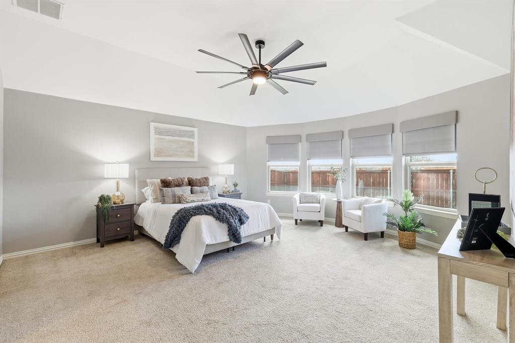 9728 Bitterroot Drive Little Elm, TX 75068 - Photo 3 of 39 LARGE private primary bedroom with seating area, large fan, norman shades, natural light and ensuite bathroom