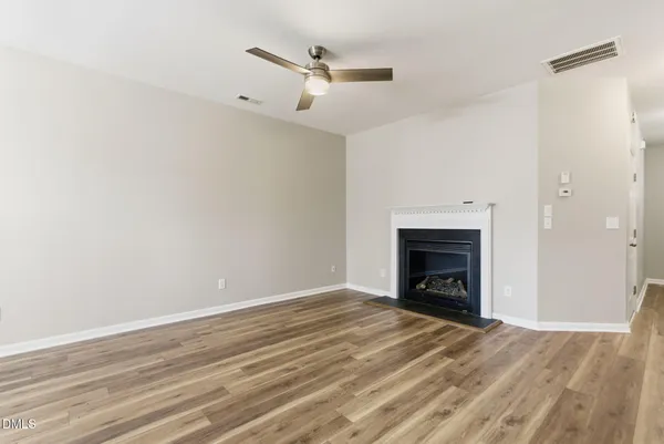 an empty room with a fireplace and a ceiling fan