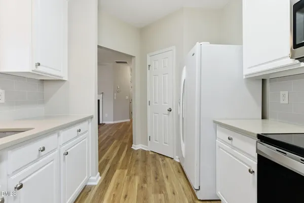 a view of a kitchen with white cabinets and wooden floor