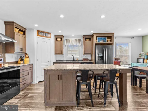 a large kitchen with granite countertop a stove a sink a dining table and chairs