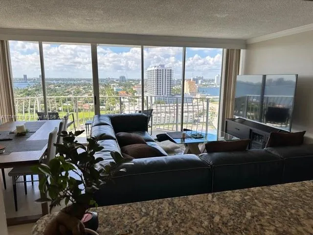 a living room with furniture large windows and wooden floor