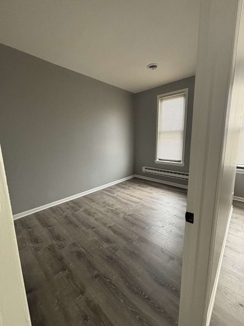 10401 South Ewing Avenue, Unit 104032 Chicago, IL 60617 - Photo 6 of 10 an empty room with wooden floor and windows
