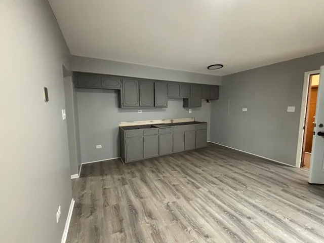 a view of kitchen and empty room with wooden floor