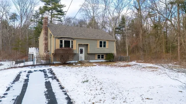 a front view of a house with a yard covered with snow in the background
