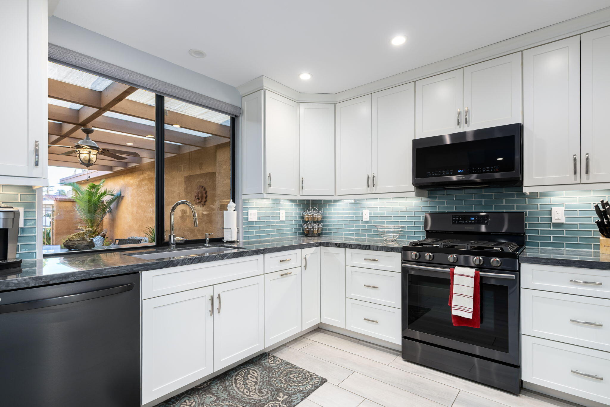 10 Palma Drive Rancho Mirage, CA 92270 - Photo 20 of 51 a kitchen with granite countertop white cabinets and black stainless steel appliances