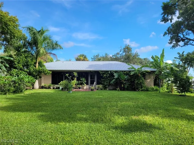 a view of a table and chairs under an umbrella in front of house
