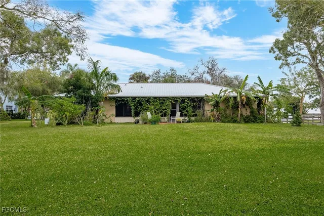 a view of a big yard with table and chairs and a large tree