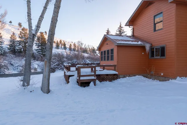a front view of a house with a yard and large trees