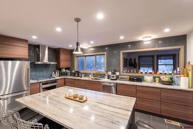 a kitchen with a refrigerator a stove a sink and chairs