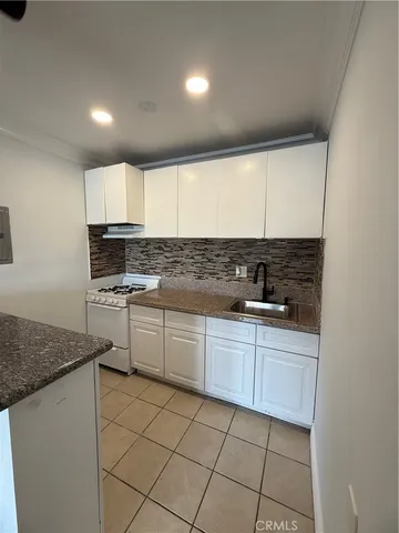 a kitchen with granite countertop white cabinets sink and white appliances