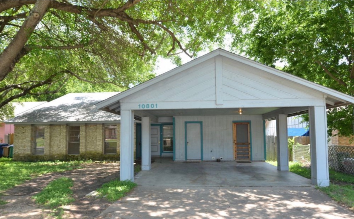 View of front of property with concrete driveway, a patio area, brick siding, and an attached carport