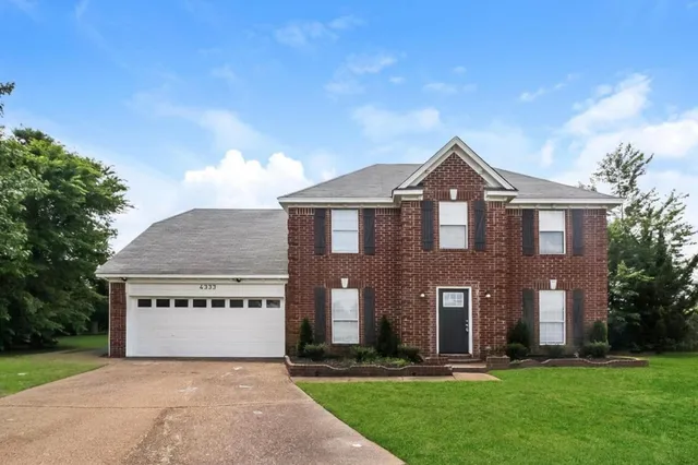 a front view of a house with a yard and trees