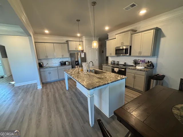 a kitchen with a sink stove and wooden floor