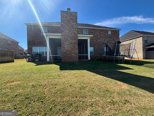 a view of a brick house with a yard and large tree