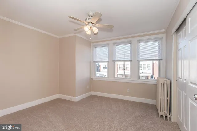 an empty room with windows and chandelier fan