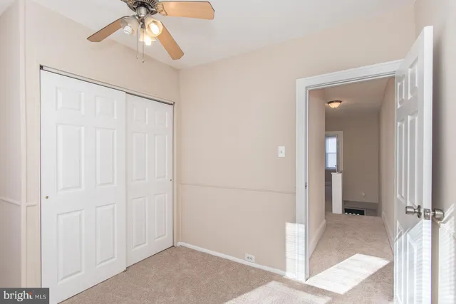 an empty room with chandelier fan and windows