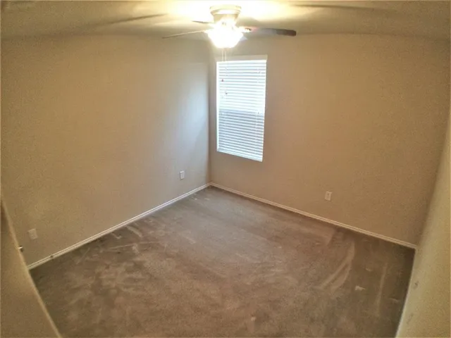 en empty room with windows and chandelier fan