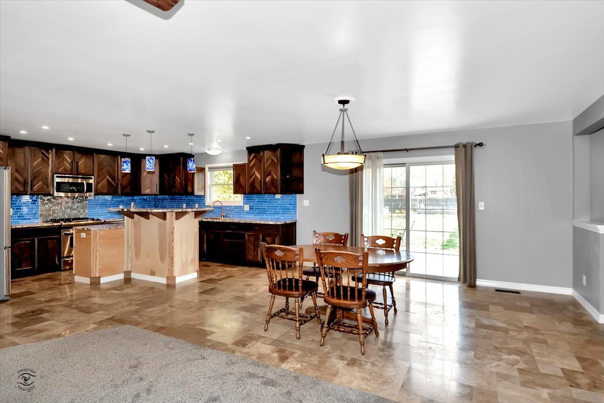302 North Raven Road Shorewood, IL 60404 - Photo 5 of 26 a kitchen with stainless steel appliances kitchen island granite countertop a table chairs sink and cabinets