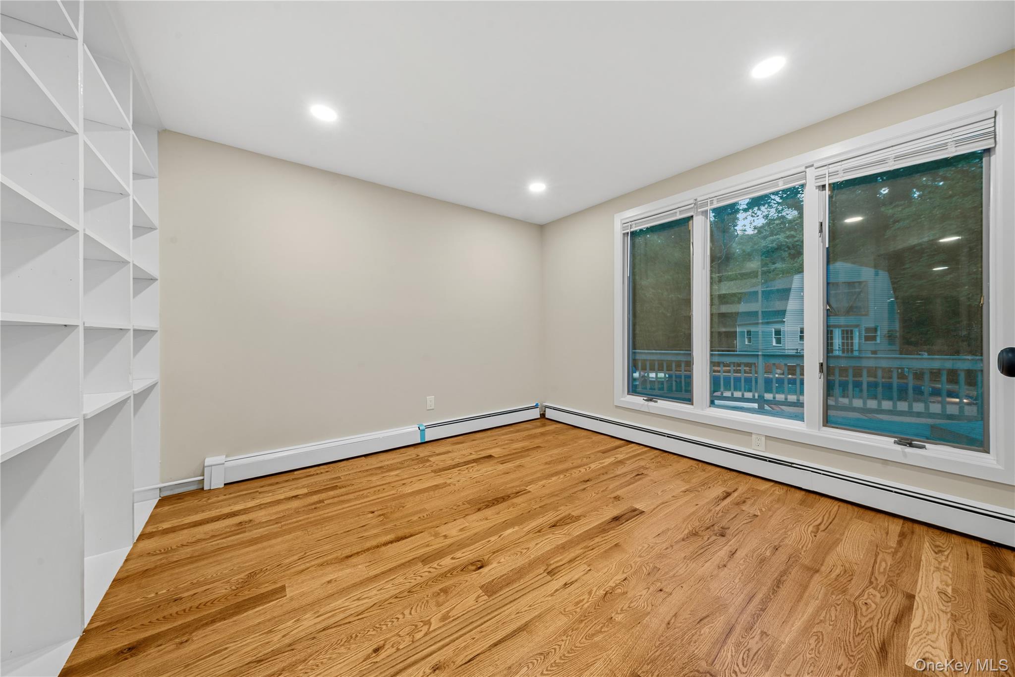 57 Eastwood Road Miller Place, NY 11764 - Photo 11 of 45 a view of an empty room with a window and wooden floor