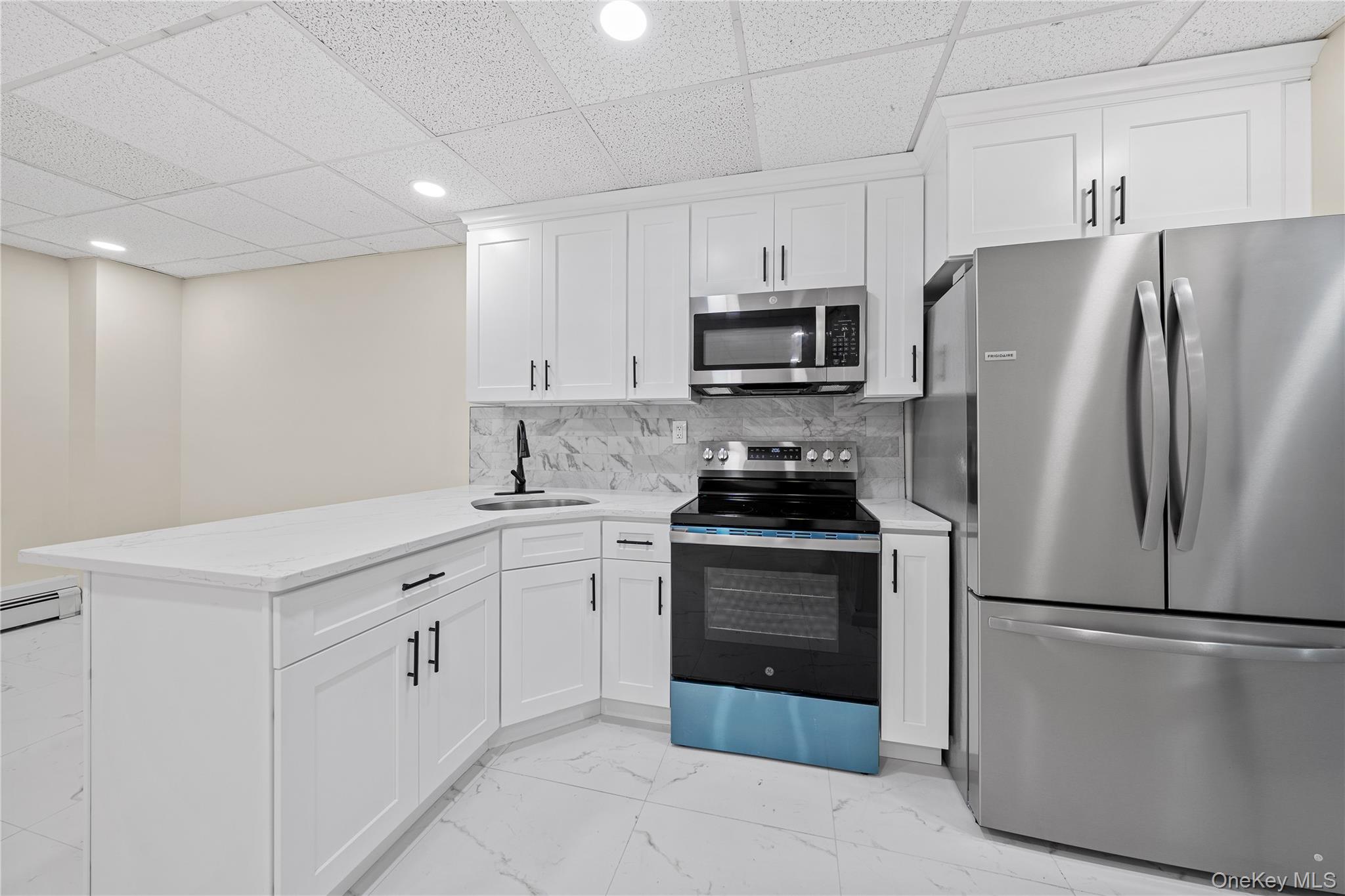 57 Eastwood Road Miller Place, NY 11764 - Photo 29 of 45 a kitchen with stainless steel appliances a refrigerator stove and white cabinets