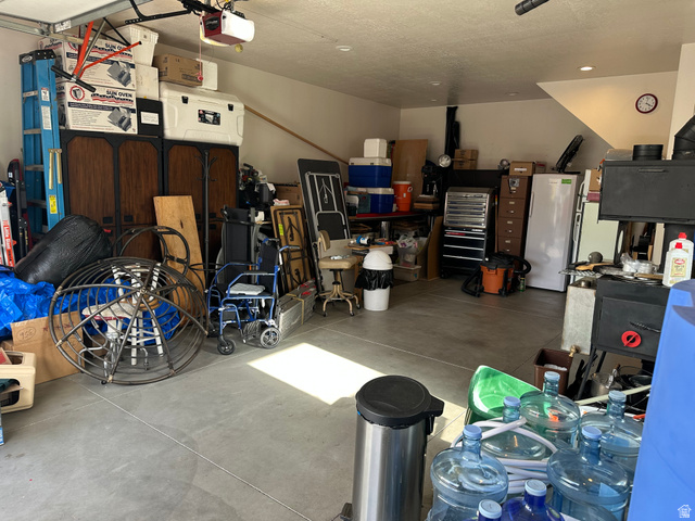 310 East 600 South Centerville, UT 84014 - Photo 30 of 41 Spacious garage featuring a concrete floor, overhead garage door, built-in shelving, wood-burning stove, and recessed lighting