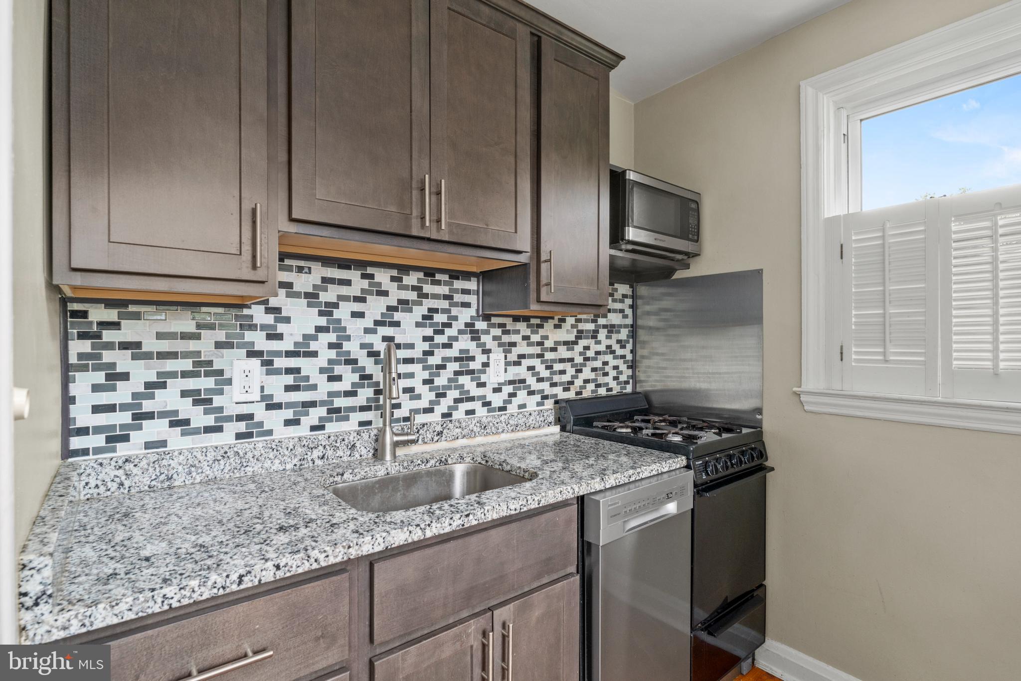 5708 Rockspring Road, Unit B Baltimore, MD 21209 - Photo 6 of 19 a kitchen with granite countertop a sink a stove and cabinets