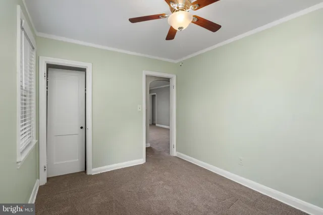 an empty room with closet and a chandelier fan