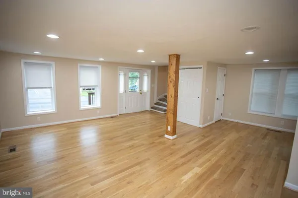 a view of an empty room with wooden floor and stairs