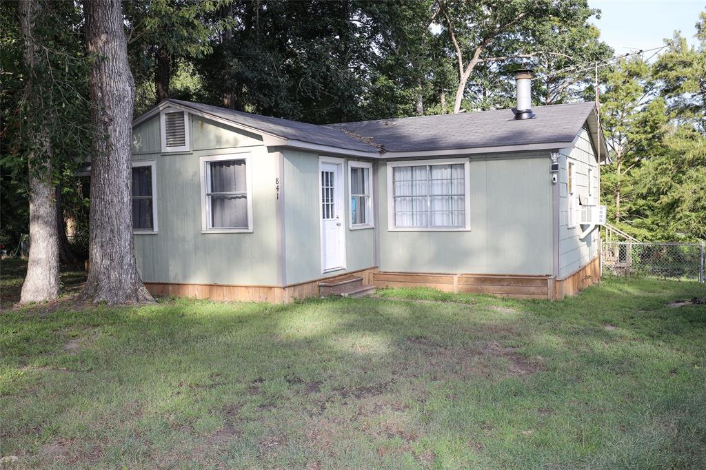 a view of a yard in front of a house with plants and large tree