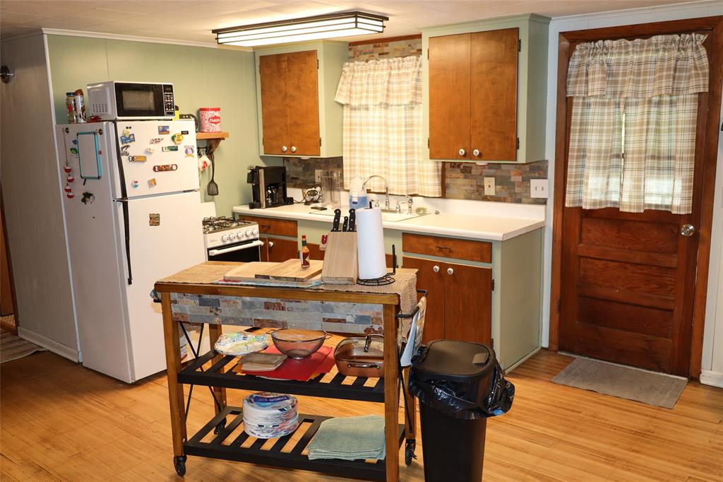841 Dogwood Trail Logansport, LA 71049 - Photo 18 of 40 a kitchen with stainless steel appliances granite countertop a stove a refrigerator and a dining table with wooden floor