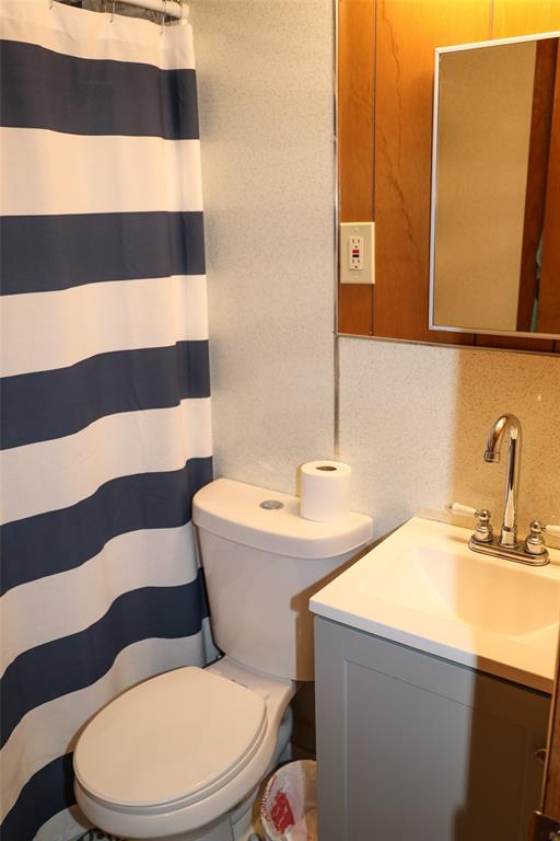 841 Dogwood Trail Logansport, LA 71049 - Photo 23 of 40 a bathroom with a sink a toilet a mirror and shower curtain
