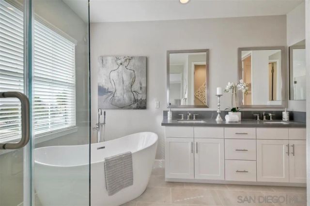 a bathroom with a granite countertop tub a double vanity sink a window and a mirror