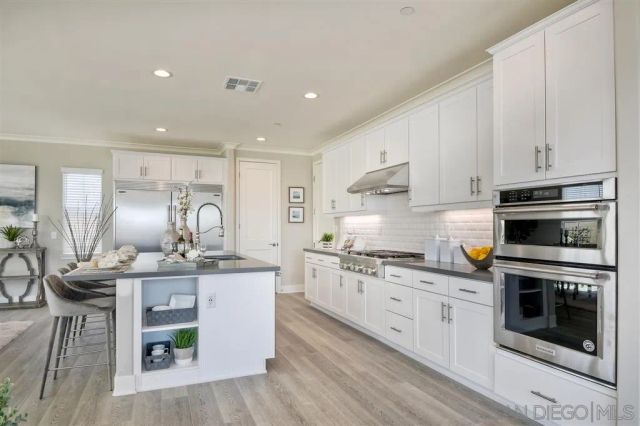 a kitchen with stainless steel appliances granite countertop a stove a sink and a refrigerator