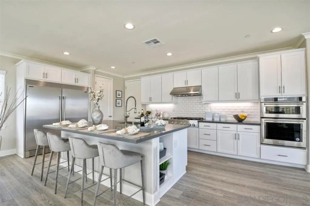 a kitchen with stainless steel appliances kitchen island granite countertop a stove a sink a refrigerator and white cabinets