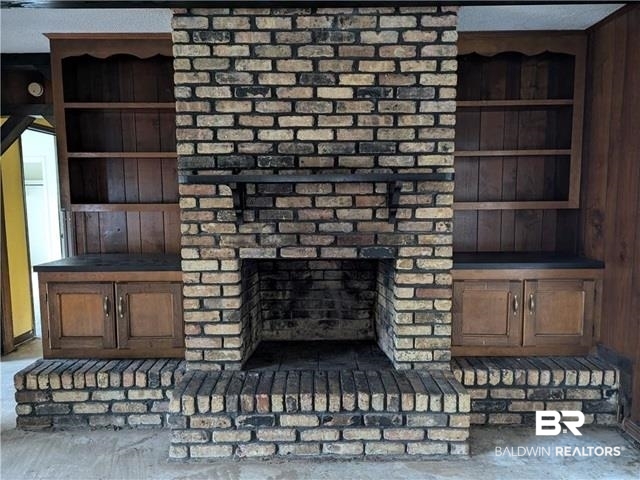3817 Lansdowne Circle Mobile, AL 36693 - Photo 12 of 16 Interior details featuring wooden walls, concrete floors, and a brick fireplace