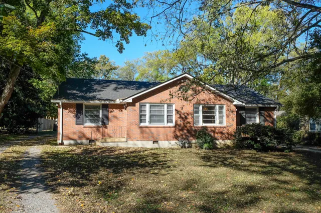 a front view of house with yard and trees in the background