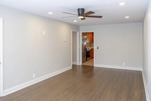 an empty room with wooden floor and a ceiling fan