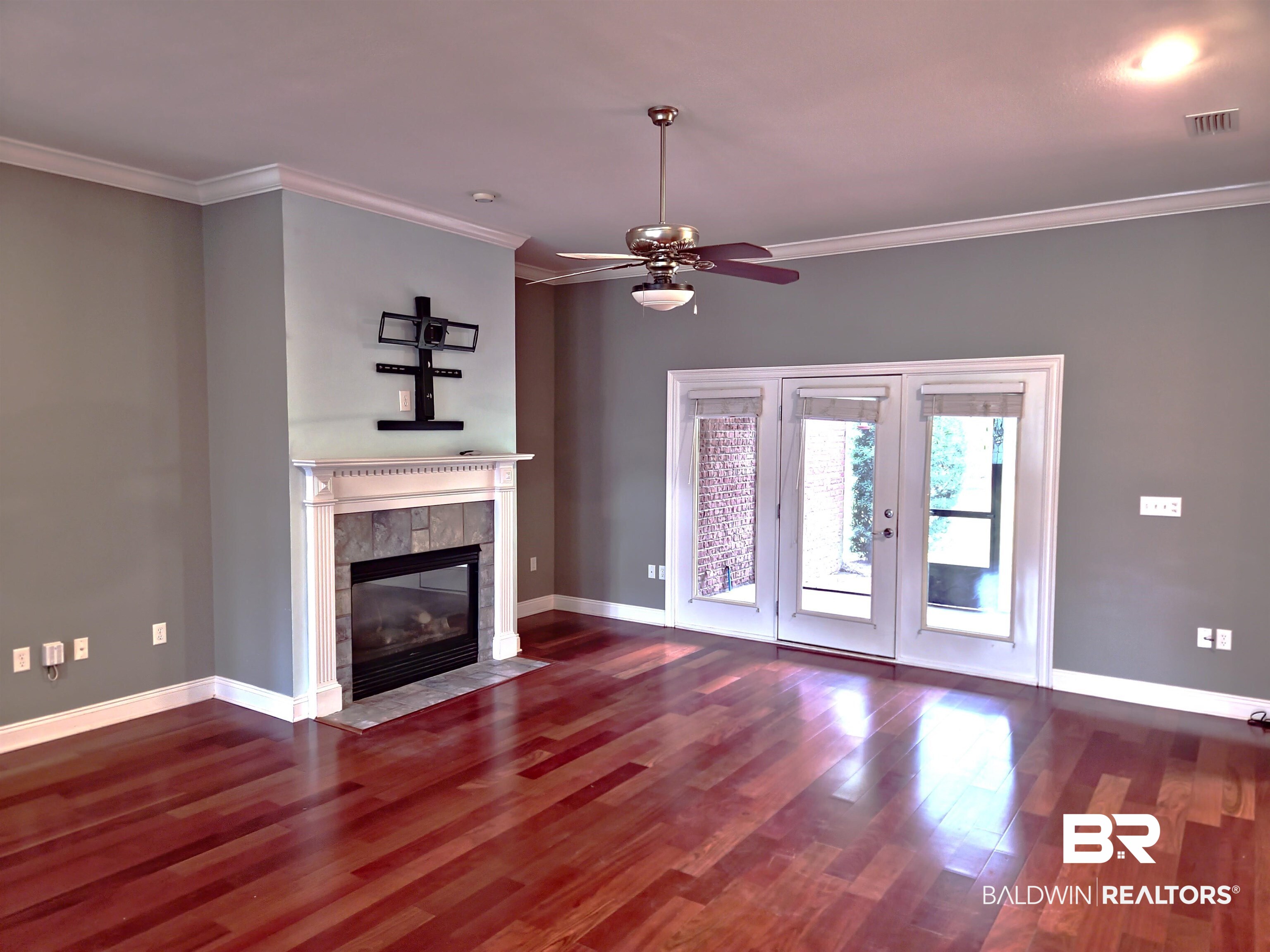 306 South Tee Drive Fairhope, AL 36532 - Photo 11 of 37 Unfurnished living room featuring ceiling fan, dark hardwood / wood-style flooring, crown molding, and a tiled fireplace