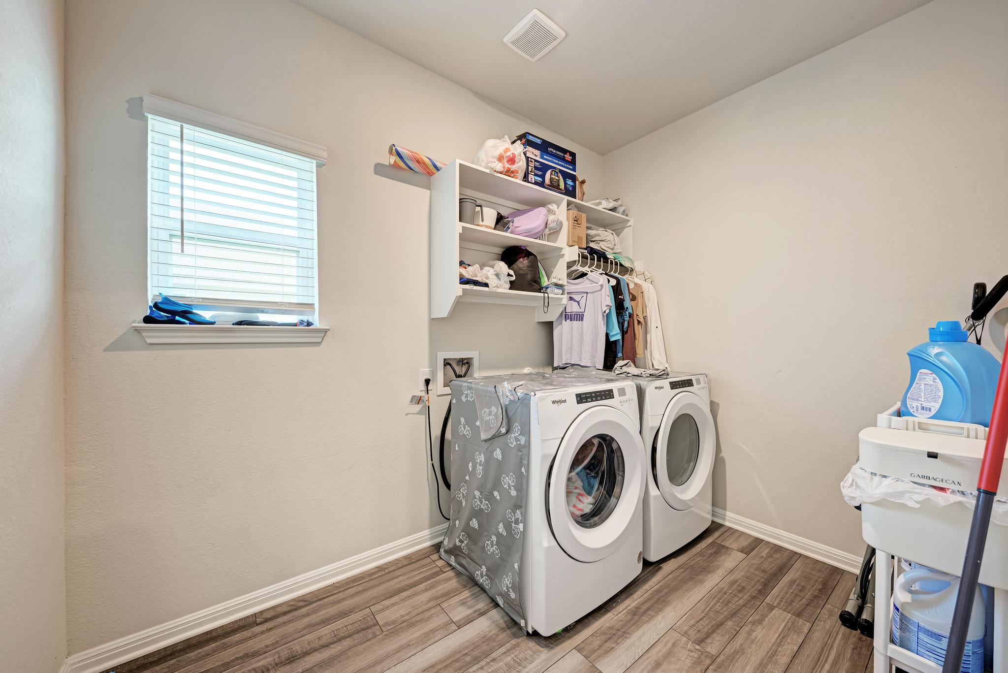 305 Windy Reed Road Hutto, TX 78634 - Photo 26 of 35 Functional laundry setup highlights durable wood-look flooring and built-in shelving overhead.