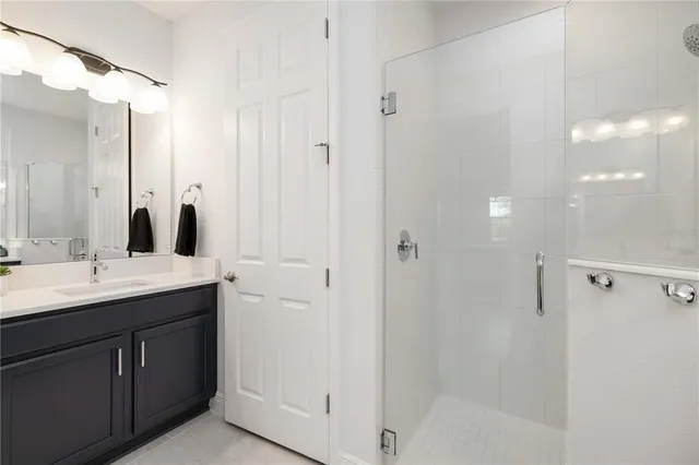 a bathroom with a granite countertop sink two mirror and a shower