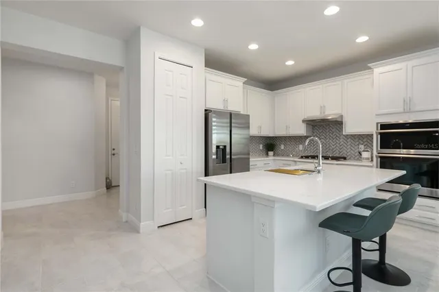 a kitchen with a sink a refrigerator and white cabinets