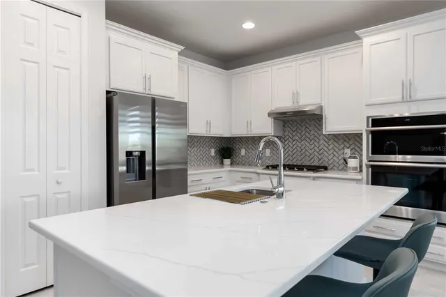 a kitchen with granite countertop a refrigerator stove and sink